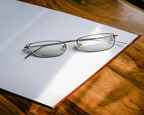 Livre ouvert avec lunettes posé sur une table en bois